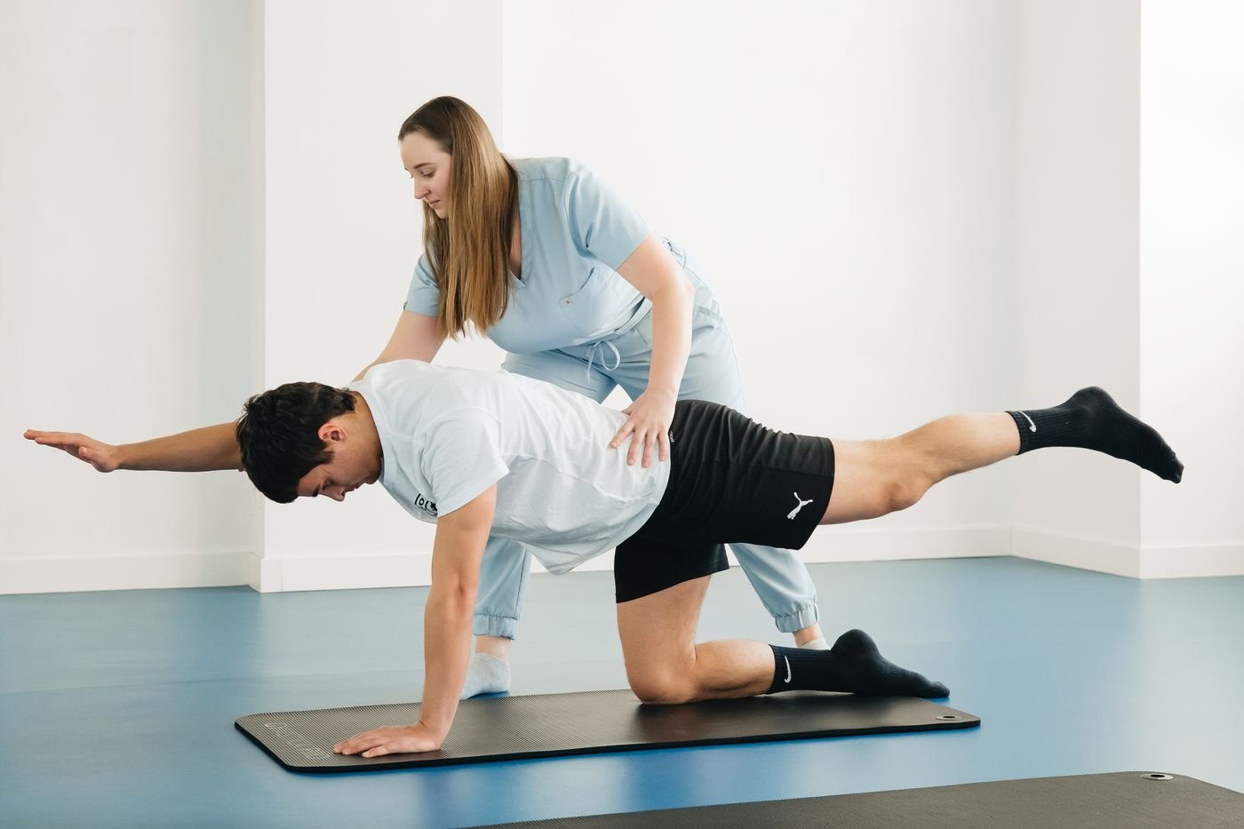 Physiotherapist guiding an adult through a movement exercise